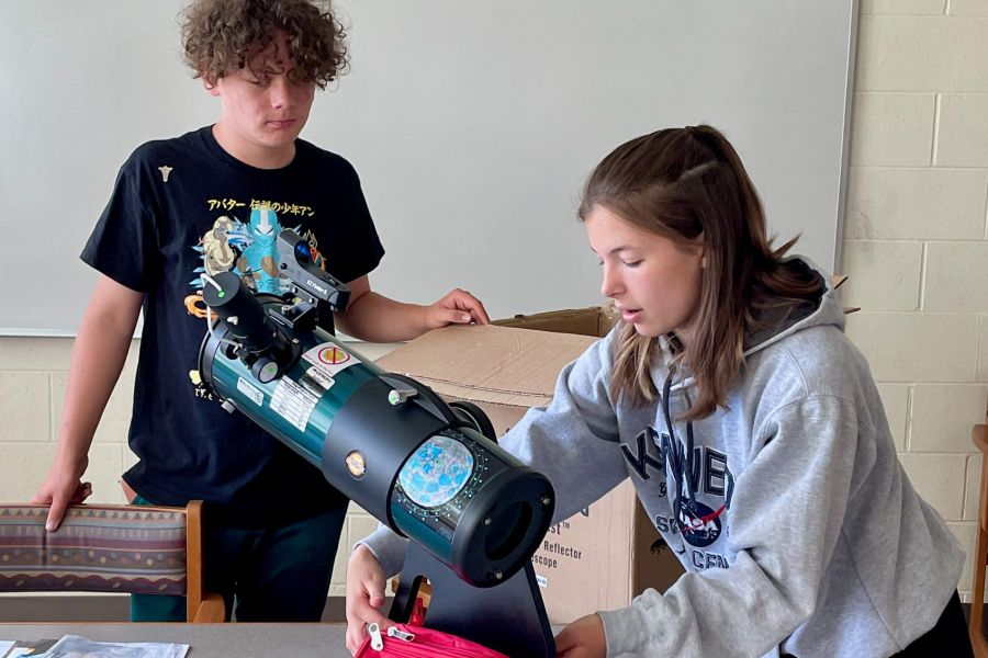 Student showing telescope to classmate